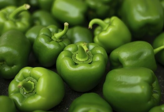 Vibrant green bell peppers with glossy skin scattered on dark textured surface
