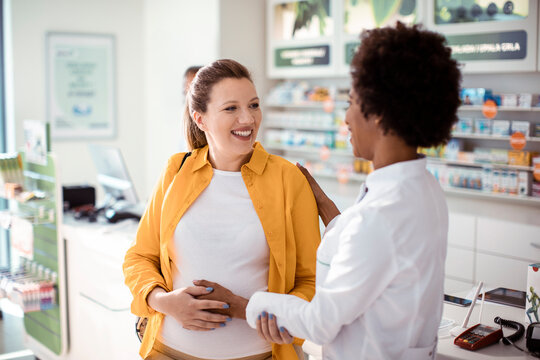 Female pharmacist helping pregnant woman in drug store