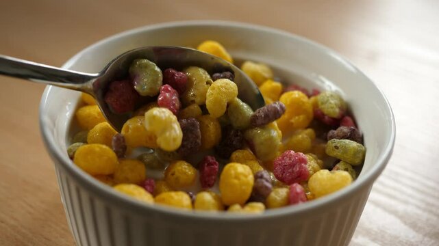 slow motion scooping colorful fruity cereal with a spoon from a bowl full of milk