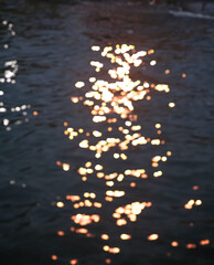 Blurred Shimmering sunlight dances on the water's surface, creating a mesmerizing pattern of golden sparkles. The blurred background enhances the magical effect.