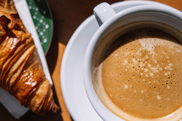 Top view of a tasty breakfast of coffee and croissant with wooden background in a French style cafe.