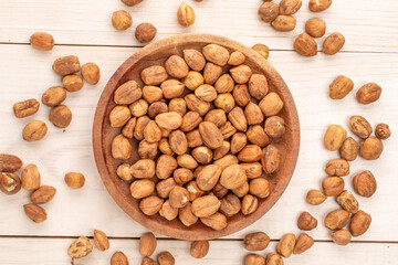 Hazelnuts in a wooden plate on a wooden table, close-up, top view.