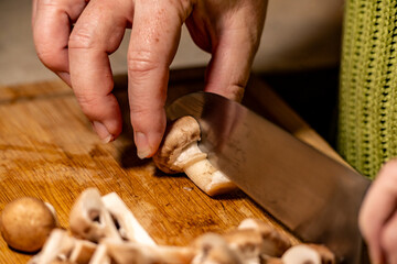 gros plan, de la découpe de champignon de Paris brun, avec un couteau chef sur une planche à découper