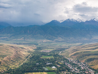 Obraz premium Drone view of the village and mountains before the rain. Large clouds on the sky. Evening landscape.