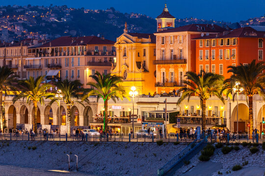 NICE, FRANCE - AUGUST 29, 2019: people walking at night, "Promenade des Anglais", Walkway of the English, pedestrian street along the beach, French Riviera of Mediterranean Sea