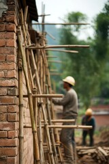 Construction workers using bamboo scaffolding on a brick wall during building project in a rural setting