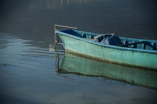 Blaues Boot steht auf dem See. Es gibt eine Spiegelung des Bootes im Wasser.