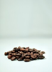 Handful of brown aromatic coffee beans isolated on vertical white background with empty copy space for text.