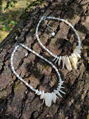 Mother of pearl necklaces, pair of beage irregular stone chokers on tree bark background, nacre...