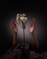 Female hands with clay human heart on gray background