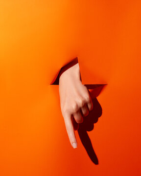Hand points down through bright orange background