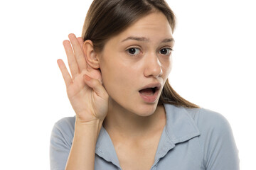 Fototapeta premium Young surprised woman isolated on white background listening to something by putting hand behind the ear.