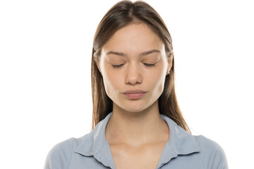 Fototapeta premium Portrait of a beautiful young serious woman without makeup and with closed eyes on a white studio background