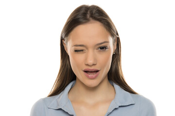 Portrait of a beautiful young winking woman with makeup on a white studio background