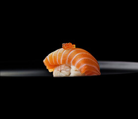 A beautifully crafted salmon nigiri sushi with tender slices of fresh salmon over perfectly seasoned rice, topped with vibrant salmon roe. A minimalist black background enhances its elegant appeal.