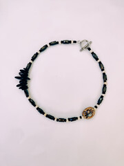 Black stone beaded necklace at pink background close up top view. Hematite, magnetite semiprecious...