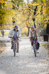 Obraz premium Senior couple riding bicycles together through an autumn park, laughing and enjoying an active lifestyle, showcasing fun, health, and companionship in a vibrant outdoor setting