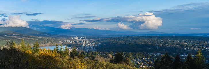 Panoramic aerial view of Fraser Valley as seen from Burnaby Mountain, BC, with mountains in silhouette on horizon.