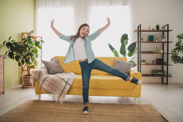 Joyful young girl in casual denim outfit enjoying carefree day indoors in modern home