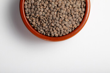 Earthenware bowl full of lentils on a white background in an zenithal  photograph