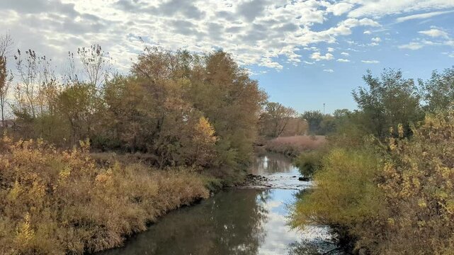 The deciduous trees and prairie have changed to their fall colors. Water flows gently over rocks in Clear Creek, Coralville, Iowa, United States.
This time-laps shows the flowing creek and the flowing