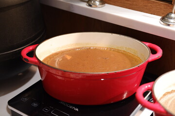 red pot filled with a creamy soup or sauce, sitting on a stovetop