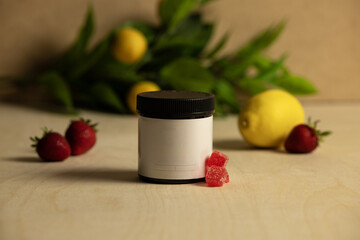 Blank label with amber vitamin gummy jar with strawberry and lemons on a rustic wood background