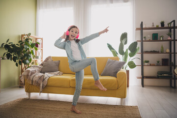 Fototapeta premium Happy young girl dancing to music in cozy living room with daylight streaming through windows