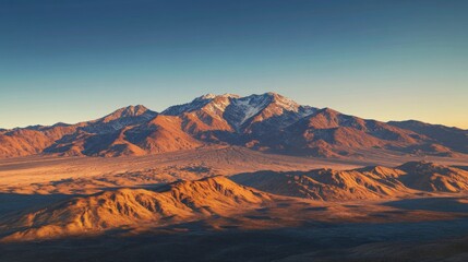 Naklejka premium Majestic snow-capped mountain range at sunset, vast desert landscape.