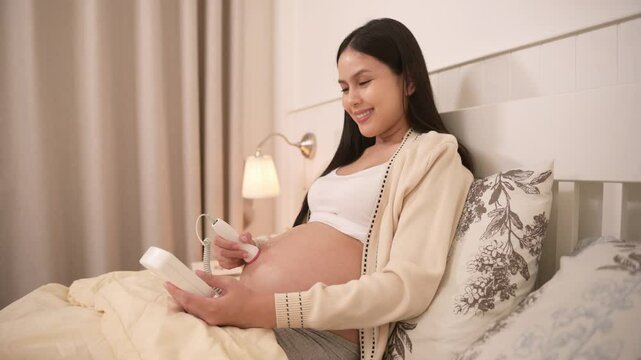 Pregnant woman holding pocket fetal doppler to listen baby heartbeat on belly