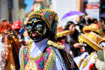 Dancers with masks and traditional costumes celebrate the festivity of the Virgen del Carmen in the square of Paucartambo. Cusco Peru.