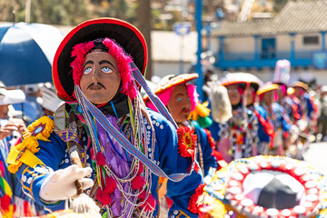 Dancers with masks and traditional costumes celebrate the festivity of the Virgen del Carmen in the square of Paucartambo. Cusco Peru.