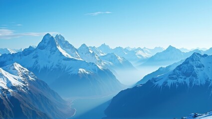  Snow-capped mountains under a clear blue sky, with a river winding through the valleys. Sunlight illuminates the peaks, creating shadows that add depth and highlight the natural beauty