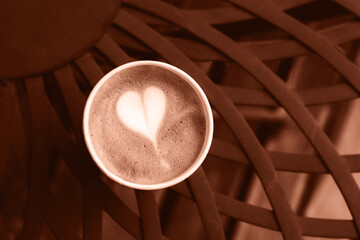 Coffee in paper cup on brown vintage metal table. Top view. Demonstrating color of the year 2025 - Mocha Mousse