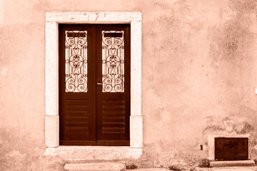 Old brown wooden door with ornament on the wall. Demonstrating color of the year 2025 - Mocha Mousse