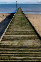 Fototapeta premium Wooden jetty leading out to sea on beach