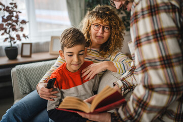 Obraz premium Mum, and dad show book to son and study together with him at home