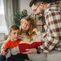 Mum, and dad show book to son and study together with him at home