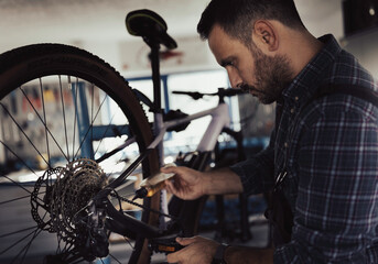 Man worker pouring oil on bicycle chain