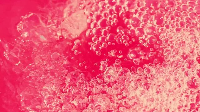 Bubbles rising rapidly in a bright red liquid filled with froth and effervescence during an experimental demonstration in a laboratory setting
