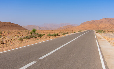 Long road through the Moroccan desert along the Atlas Mountains