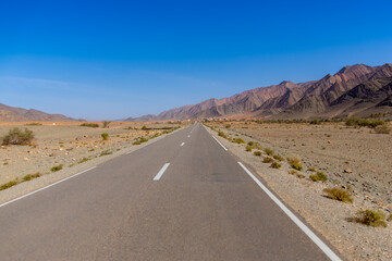 Long road through the Moroccan desert along the Atlas Mountains