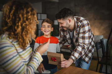 Mother, father and son read together greeting card from gift box