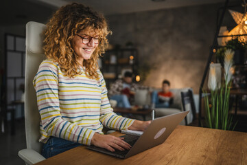 mom work from home on laptop whit his family in the background