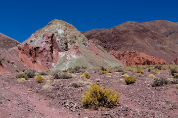 Rainbow valley mountains in Chile, Atacama desert near San Pedro de Atacama. Colorful red rock formations in summer under blue sky. Res stone valley touristic object, hiking path