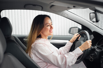 Happy driver inside the car. An Asian woman driving a car without a seat belt.