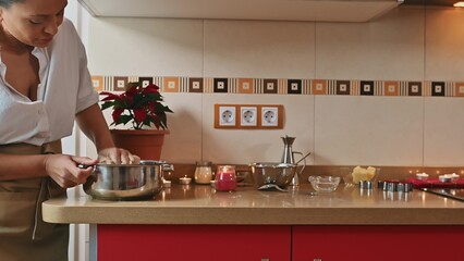 Woman preparing meal in cozy kitchen with festive decorations
