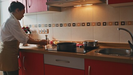 Woman in the kitchen preparing dough for baking by the stove