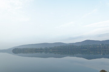 misty morning on the Lake Comabbio , very early in the morning, from the promenade of the lakefront of Varano Borghi. Italy