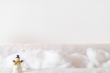 snowman figurine standing in snow with white background and room for copy